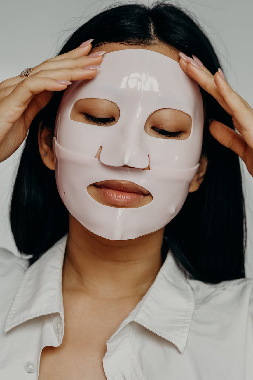 beautiful asian woman applying white sheet mask, having a relaxing self care moment